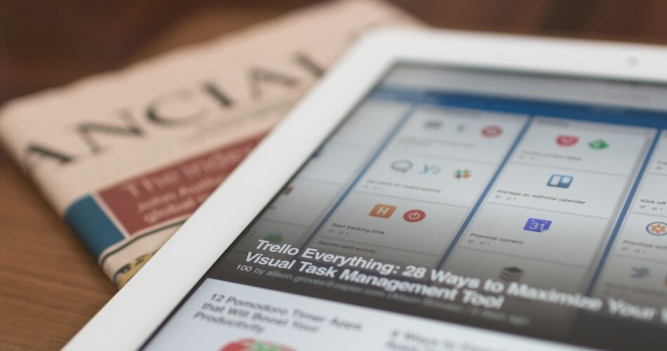 white tablet computer on top of newspaper