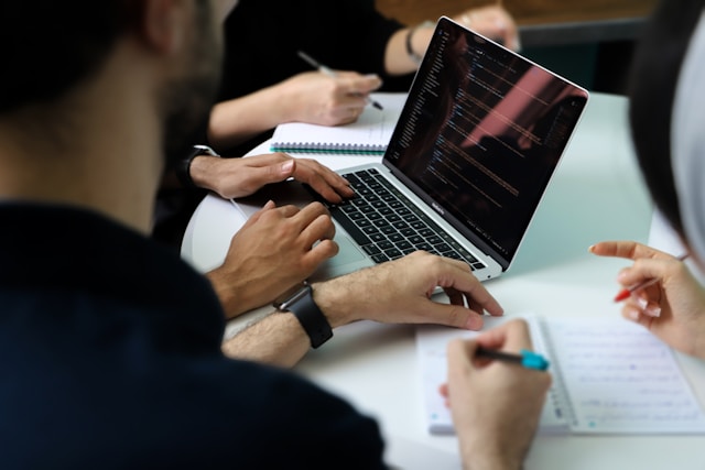 a-group-of-people-sitting-around-a-laptop-computer